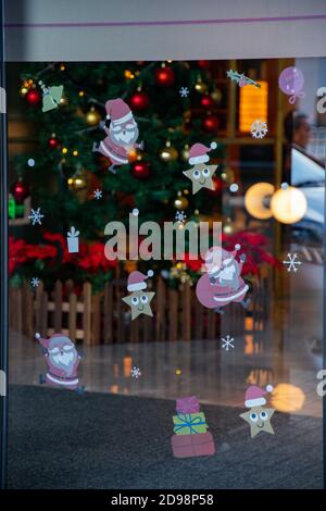 Defocus reflections in glass window with holiday pattern stickers on transparent surface with blurry lights and silhouettes behind. Abstract Christmas Stock Photo