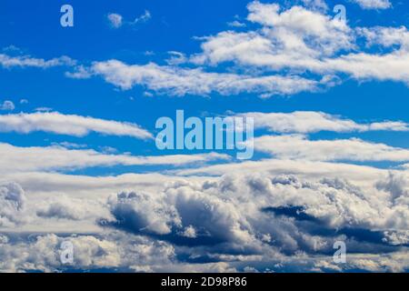 Bright blue sky with dramatic cumulus clouds lit by the daytime sun. Abstract background. Stock Photo
