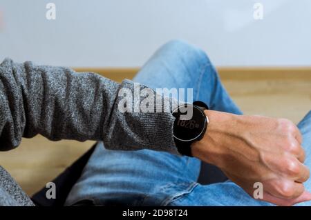 Hand wearing elegant smartwatch with clock app. over the shoulder view. Stock Photo