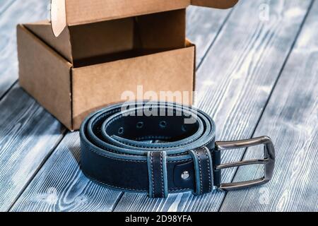 Belt with metal buckle. The belt is rolled up, next to a gift box. Template for the design of leather accessories. Background, shiny metal belt buckle. Abstract background. Texture background Stock Photo