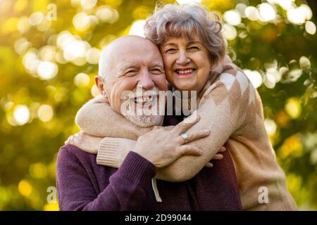 Happy senior couple spending time together in beautiful city park in autumn Stock Photo