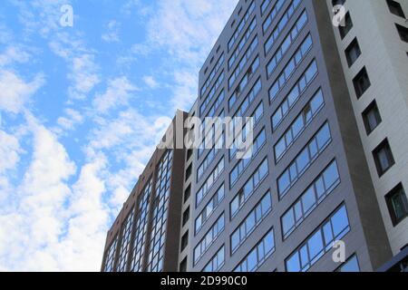 Wall of a multi-storey building with windows against the sky. Plastic windows in a modern high-rise house. Bottom view. Stock photo modern urban development for web and print. Stock Photo