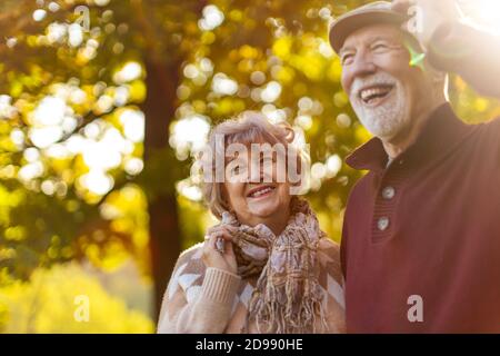 Happy senior couple spending time together in beautiful city park in autumn Stock Photo