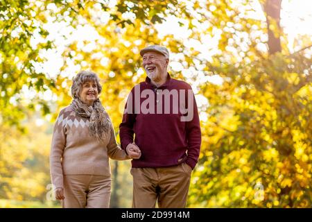 Happy senior couple spending time together in beautiful city park in autumn Stock Photo
