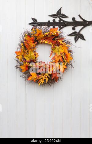 Autumn or Thanks Giving wreath ring hanging on a white painted cottage door with decorative ironmongery in an English village Stock Photo
