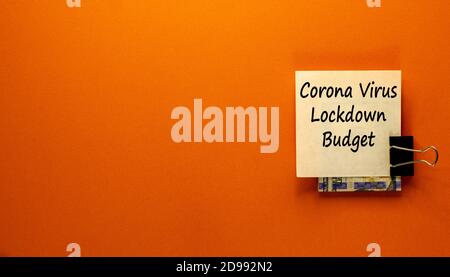 White note with text written Corona Virus Lockdown Budget clip with dollars cash money on orange copyspace background, concept of limited expense on q Stock Photo