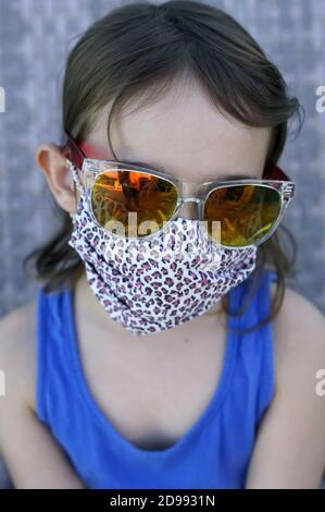 Beautiful little girl wearing a protective mask made of fabric with defocused background Stock Photo
