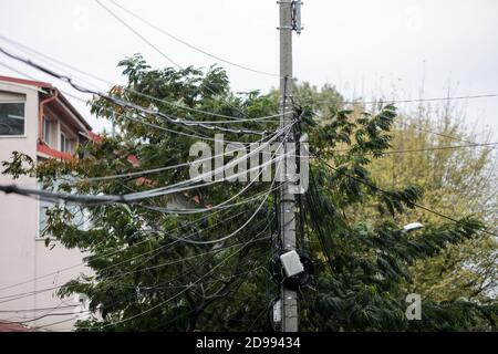 Many unorganised internet and TV cables on a concrete pole in Bucharest. Stock Photo