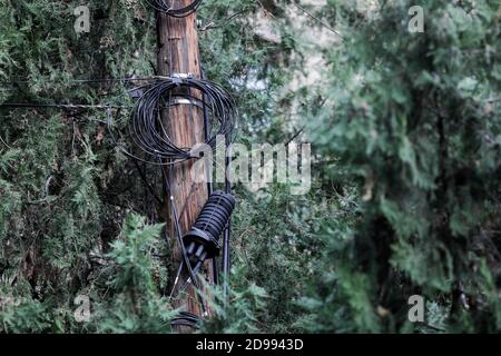 Many unorganised internet and TV cables on a wooden pole in Bucharest. Stock Photo