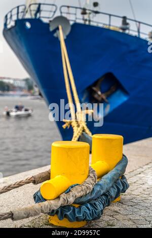 Closeup of a large blue ship anchored to a yellow steel dock anchor with thick rope. Pier at Rampart of Brave in Szczecin, Poland Stock Photo