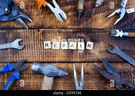 The word repair on wooden background. Various working tools are nearby. home renovation concept. Stock Photo