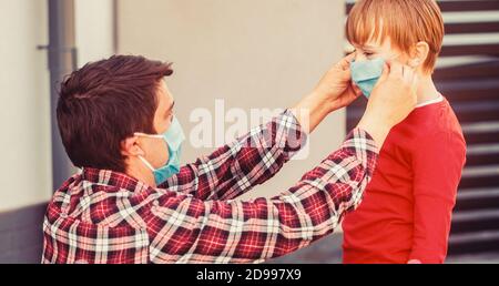 Dad with a son in a medical mask. Father puts a medical mask on her son. Coronavirus, illness, infection, quarantine, medical mask Stock Photo