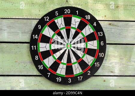 Dartboard mounted on green wooden wall, front view. Close-up photo background Stock Photo