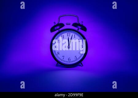Alarm clock on a pink-blue background. Isolated object. Stock Photo