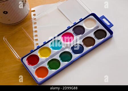 Watercolor Paint Set on White Paper on a Wooden Desk Stock Photo