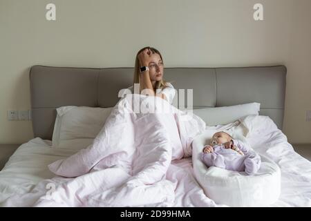Tired Mother Suffering from experiencing postnatal depression. Health care mom motherhood stressful. Stay at home during coronavirus covid-19 pandemic Stock Photo