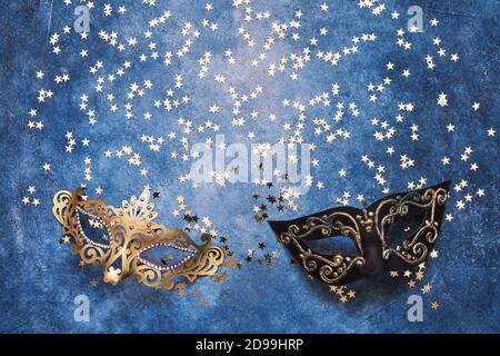Two carnival mask and golden stars on a blue background. Top view, copy space. Carnival party celebration concept. Stock Photo