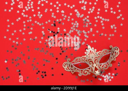 Golden carnival mask and golden stars on a red background. Top view, copy space. Carnival party celebration concept. Stock Photo