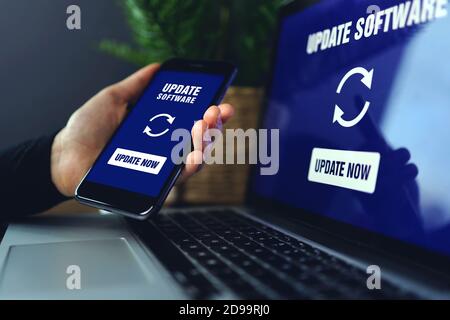 Hand holding smartphone doing installing update process with gearbox percentage progress and loading bar with installing update on screen laptop backg Stock Photo