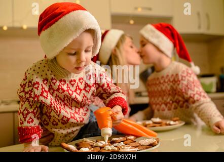 Beautiful mom and little sons decorating gingerbread Xmas cookies Stock Photo