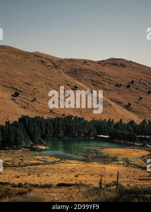 Blue oasis surrounded by green trees in the mountains of lebanon Stock Photo