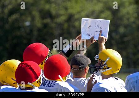 High School Football has coash pointing to play book during a practice session Stock Photo