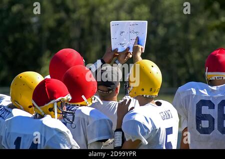 High School Football has coash pointing to play book during a practice session Stock Photo