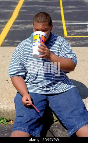 Overweight teen male drinks a high calorie content soda pop Stock Photo