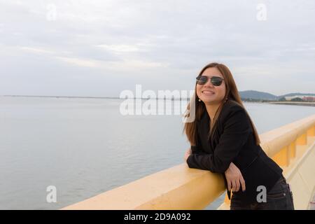 Asian woman wear black sunglass standing and smiling on the bridge Stock Photo