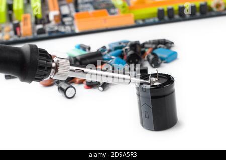 soldering iron on the background of a computer Board and capacitors in soft focus. The concept of repair and service Stock Photo