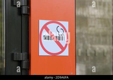 No smoking sign on orange wall, concept of health care, smoking cessation. Smoking cigarette in a crossed out red circle. Stock Photo