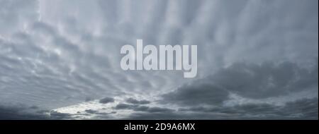 Panorama of gray dramatic sky with wavy thick clouds. Stock Photo