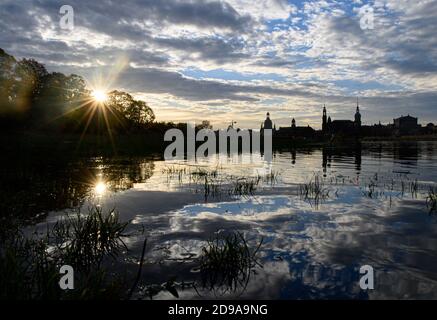 Dresden, Germany. 04th Nov, 2020. The sun rises in the morning over the old town, which is situated on the Elbe. Silhouettes of the Frauenkirche (l-r), the Ständehaus, the Hofkirche, the town hall, the Hausmannsturm and the Semper Opera House can be seen. Credit: Robert Michael/dpa-Zentralbild/ZB/dpa/Alamy Live News Stock Photo