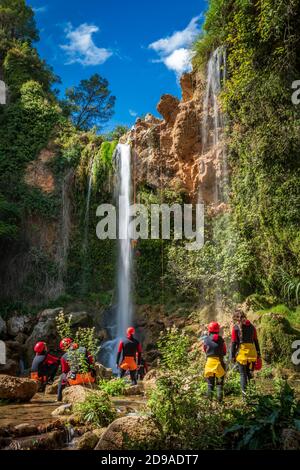 Unrecognizable people enjoy waterfall descent using ropes Stock Photo