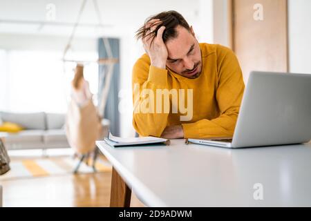 Frustrated young man working on laptop at home Stock Photo