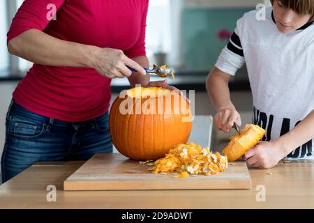 Mother and son carving halloween pumpkin in living room Stock Photo
