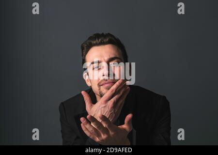 Studio portrait of a young caucasian man in a black jacket, looking at the camera, against plain studio background Stock Photo
