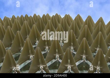 Close up view of rows of folded metallic gold triangles against a blue sky background. Stock Photo