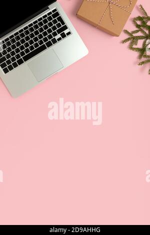 Laptop, wrapped gift and fir branch on a pink background. New Years online shopping concept with copy space. Stock Photo