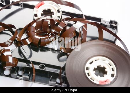 Entangled tape in disassembled audio compact cassette. Audio cassette with tape guide as security mechanism with cover removed on white surface, close Stock Photo