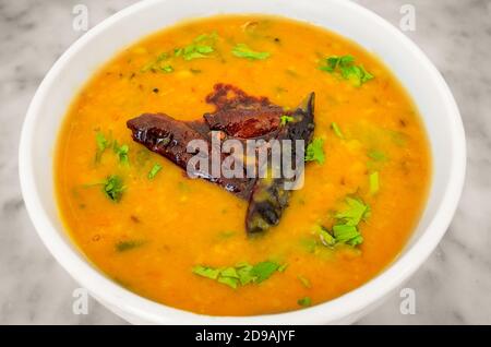 Indian Dish Lentils (Dal) Curry in a white bowl garnished with dry chillies and coriander leaves Stock Photo