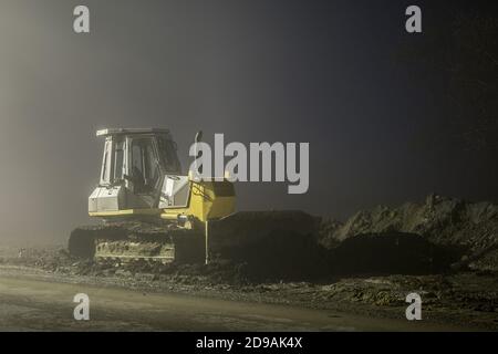 Blue excavator digger working at night on the street Stock Photo