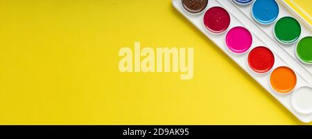 clean new palette of watercolors on a yellow paper background, copyspace Stock Photo