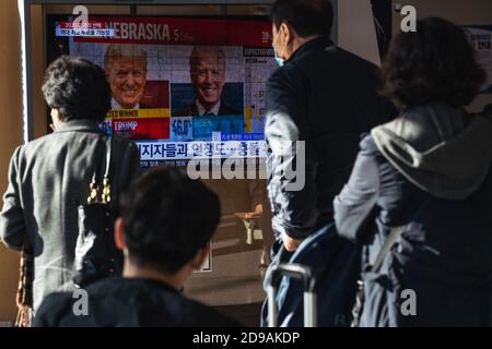 People at Seoul Train Station watch TV news report about the US Presidential election comparing Joe Biden with Donald Trump on 2020 US presidential election day. Stock Photo