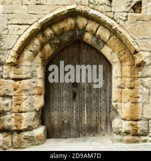 Old wooden door set in stone wall. Stock Photo