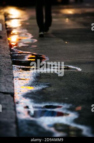 The sun in the puddles. Abstract photography reflection of the evening sun on the asphalt with a silhouette of a man in the background Stock Photo