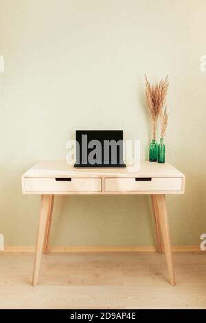 Black laptop on wooden table in home interior. Empty wall with copyspace. Stylish minimalistick workplace Stock Photo