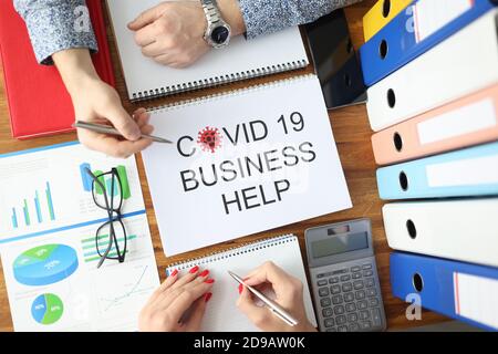 Man and woman are holding ballpoint pens over document covid 19 business help top view Stock Photo
