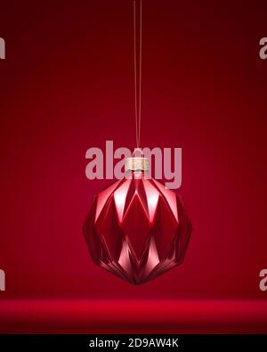 Shiny burgundy red Christmas ball hanging on golden cord. Modern geometric pattern ornament. Christmas decoration, festive atmosphere concept. Stock Photo