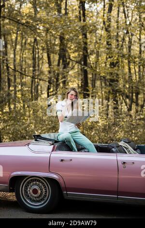 thoughtful woman in sunglasses looking at map while sitting in cabriolet in forest Stock Photo